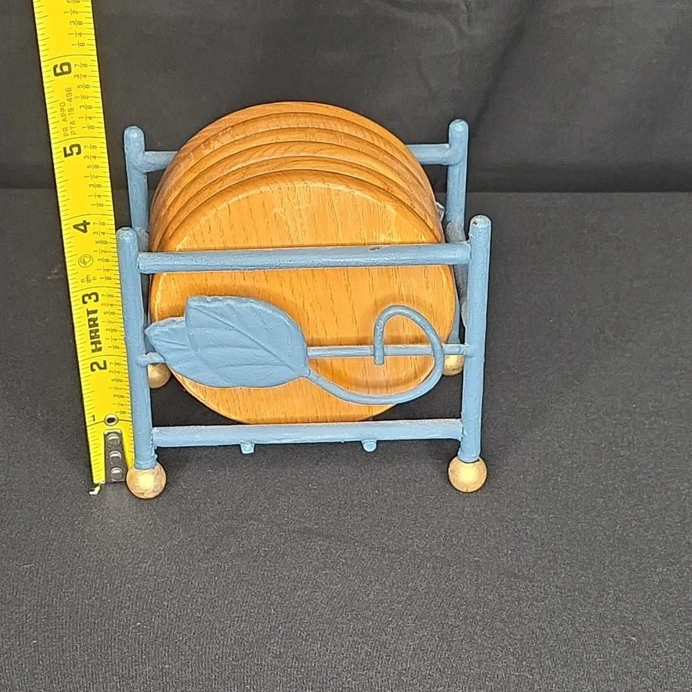 a vintage wooden drink coasters in a blue metal holder with leaf-shaped accents